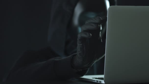 Un hacker sconosciuto che indossa una maschera nera estrae la scheda MALWARE da un computer portatile. Il concetto di hacking — Video Stock