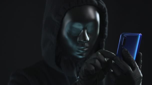 Hacker con máscara negra saca la pestaña CLAVE de un teléfono inteligente. Concepto de hackeo — Vídeo de stock