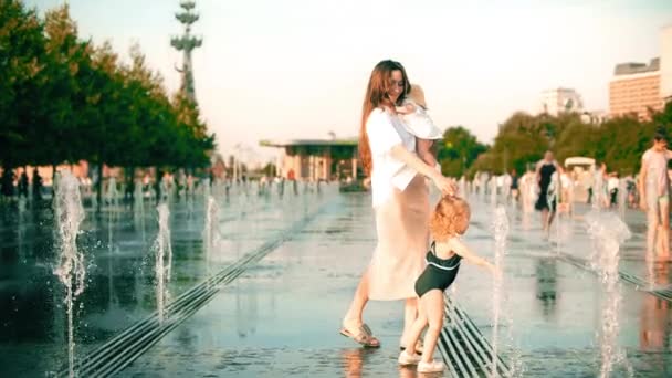 Медленный снимок мамы и ее малышей, гуляющих в фонтане городского парка в жаркий летний день — стоковое видео