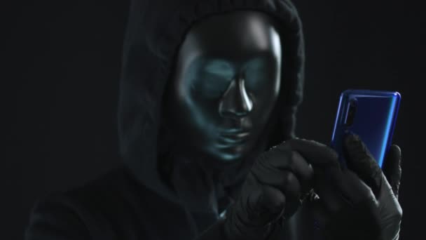 Hacker bär svart mask drar DIGITAL ID-fliken från en smartphone. Hacka koncept — Stockvideo