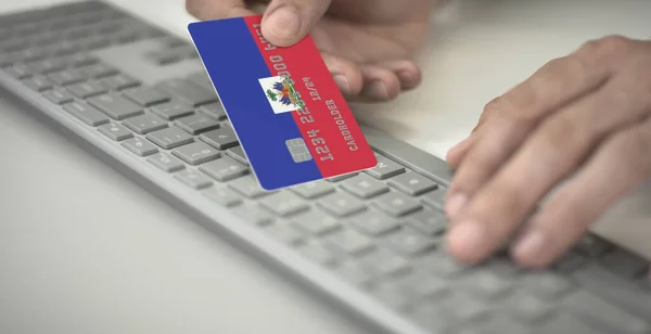 Homme inconnu paie en ligne avec une carte de crédit avec le drapeau imprimé d'Haïti. Numéros fictifs — Photo
