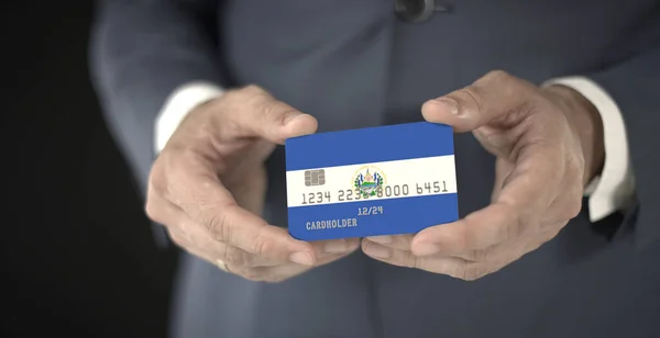Επιχειρηματίας κατέχει πλαστική κάρτα με τυπωμένη σημαία του Ελ Σαλβαδόρ στα χέρια του, φανταστικούς αριθμούς — Φωτογραφία Αρχείου