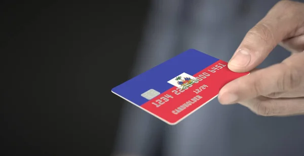 Ο άνθρωπος δίνει πιστωτική κάρτα με τυπωμένη σημαία της Αϊτής. Φανταστικοί αριθμοί — Φωτογραφία Αρχείου