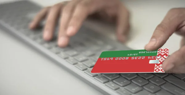 Homme paie en ligne avec une carte bancaire en plastique avec le drapeau imprimé de la Biélorussie. Numéros fictifs — Photo