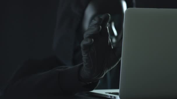 Hacker con máscara negra tira de la pestaña SPYWARE de un ordenador portátil — Vídeos de Stock