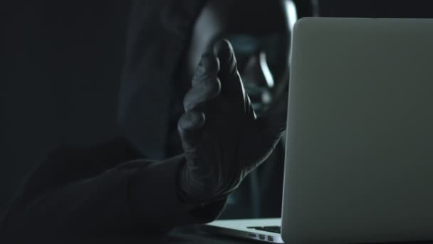 Hacker usando máscara preta puxa guia FRAUD de um laptop — Vídeo de Stock