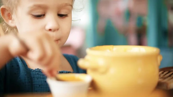 Loira bebê menina comer sopa de abóbora — Fotografia de Stock