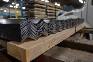 Müşterilere teslim etmek için ahşap paletin üzerinde bir yığın çatılı çarşaf.