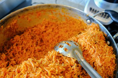 Bir kap Nijerya Jollof pirinci ile servis kaşığı