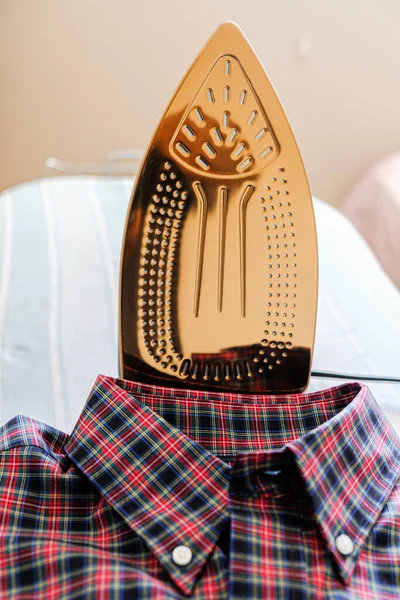 Folded Shirt with electrical iron on Ironing board — Stock Photo, Image