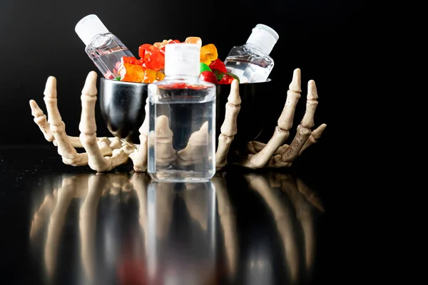 Skelett Kralle Hände mit Süßigkeiten und Hand Sanitizer - Halloween-Konzept — Stockfoto