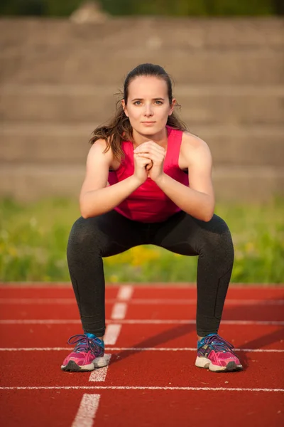 Frau Trainiert Auf Leichtathletikbahn Und Macht Kniebeugen — Stockfoto