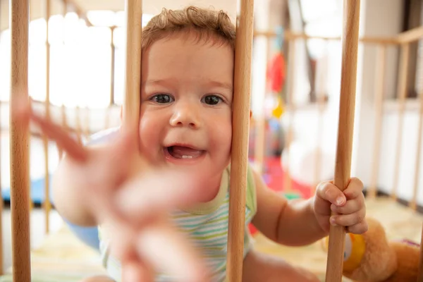 Cute Baby Uśmiechający Się Patrząc Przez Drewniane Słupki Jego Łóżeczko — Zdjęcie stockowe