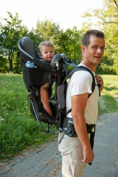 父亲在散步与巡查击壤在儿童载体背包 — 图库照片