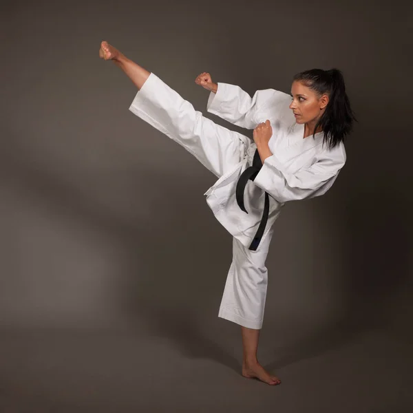 Woman in white  kimono kicks high in the air -  a karate  martial art girl
