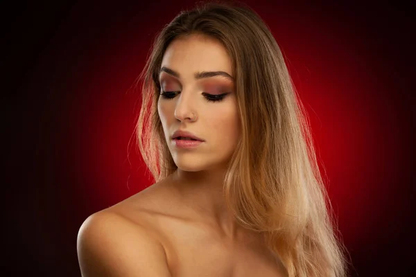 濃い赤の背景に茶色の長い髪を持つ美しい若い女性の美しさの肖像画 — ストック写真