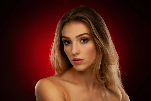 濃い赤の背景に茶色の長い髪を持つ美しい若い女性の美しさの肖像画 — ストック写真