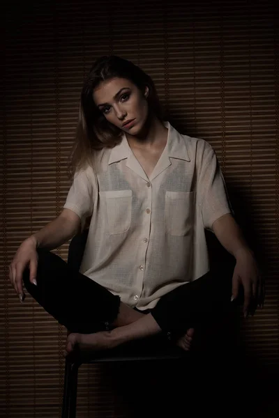 时尚年轻女子坐在椅子上机智木墙的背景 — 图库照片