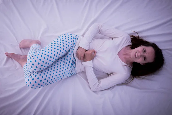 Jonge brunette Kaukasische vrouw met pijn in haar maag menstrua — Stockfoto