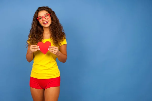 Hermosa joven en rojo sosteniendo un corazón para el día de San Valentín — Foto de Stock