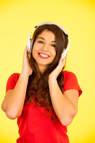 Bela jovem mulher no vermelho t-shirt ouvir música sobre amarelo ba — Fotografia de Stock