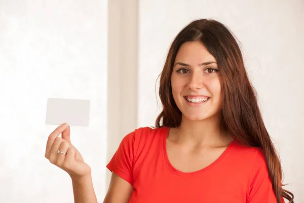 Beautiful young woman in red t shirt holds blank card over white — Stock Photo, Image