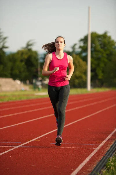 Hermosa joven corredora correr en una pista a principios de verano afte —  Fotos de Stock