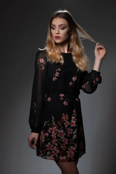 Krásná módní žena v černých šatech s květinovým Paternem — Stock fotografie
