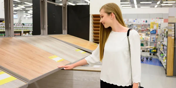 Retrato de mujer joven sonriente eligiendo pisos laminados de madera Imagen de archivo