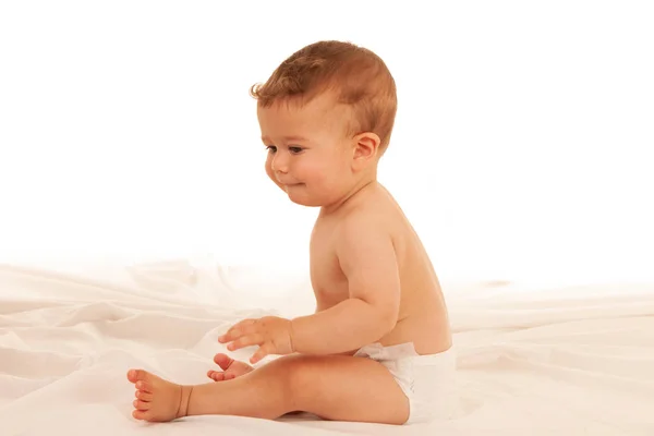 Glücklicher kleiner Junge beim Spielen auf dem Bett isoliert über weiß — Stockfoto