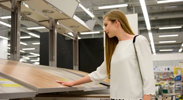 Portrait of young smiling woman choosing wood laminated flooring — Stock Photo, Image