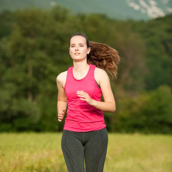 Bela jovem mulher treino ao ar livre corre através do prado no conde — Fotografia de Stock