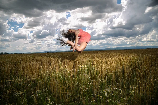 Elegant ballerina of a woman jumping in nature
