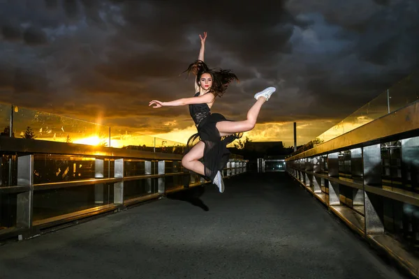 A beautiful ballerina of a woman jumping on the bridge