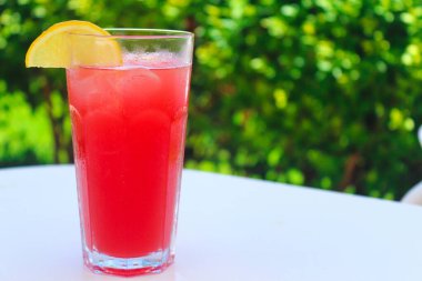 Taze buzlu egzotik kokteyl masada bulanık yeşilliğin arka planına karşı. Yaz tatili ve eğlence konsepti. Metin için alanı kopyala.