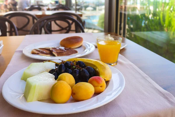 Continental breakfast served with fruits. Apricots, melon, grapes, banana, and orange juice. Vegetarian breakfast Morning, healthy food. Selective focus — Stock Photo, Image