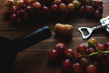 Şarap şişesi, mantar, üzüm ve ahşap arka planda tirbuşon. Şarap arka planı. Yakın plan.