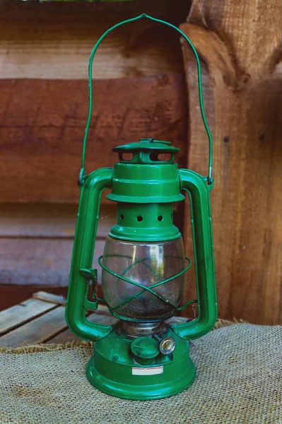 Old vintage and rusty green kerosene lamp on the wooden background — Stock Photo, Image