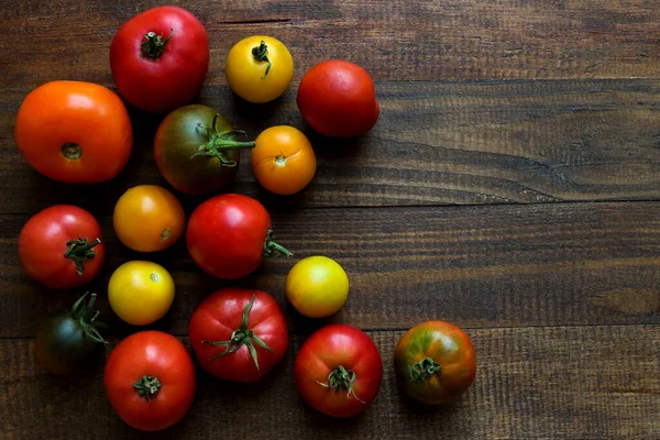 Hasat konsepti. Ahşap zemin üzerinde farklı domates türleri ve fotokopi alanı. Üst görünüm, düz görünüm, seçici odak.