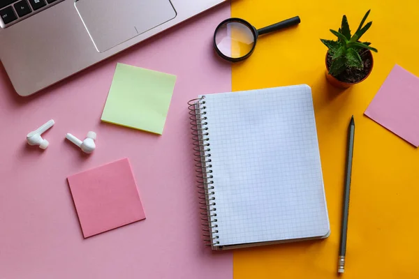 ノートパソコン ワイヤレスヘッドフォン オープンノートブックとピンクと黄色の背景に空白のシートを備えたモダンでトレンディーなワークスペース 教育とビジネスの概念 トップビュー フラットレイアウト — ストック写真