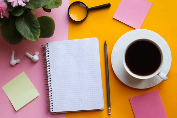 Onderwijs en bedrijfsconcept. Moderne werkruimte met open notitieboek, plant, potlood, koffie en blanco vel op roze en gele achtergrond. Bovenaanzicht, platte lay, mockup of kopieerruimte voor tekst — Stockfoto