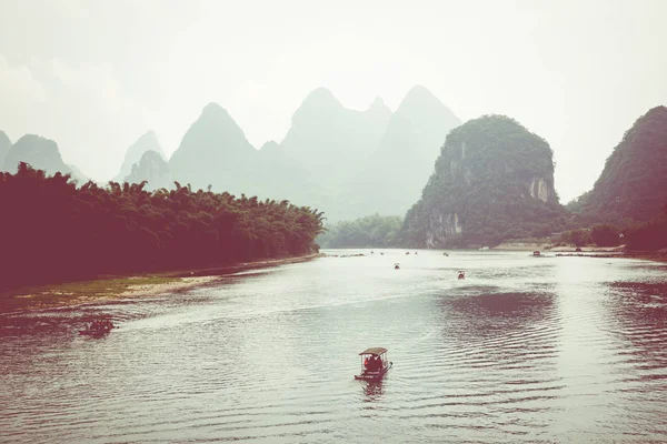 Scenic view of small tourist bamboo rafts sailing along the Li River among green woods and karst mountains at Yangshuo County of Guilin, China. Yangshuo is a popular tourist destination of Asia.