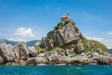 View of beautiful islets Katic (Katich) and Sveta Nedjelja with church on one of them in the sea near Petrovac, Montenegro. clipart