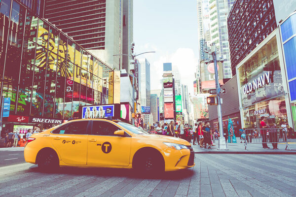 NEW YORK - SEPTEMBER 2, 2018: Yellow cab speeds through Times Square the busy tourist intersection of neon art and commerce and is an iconic street of New York City, USA.