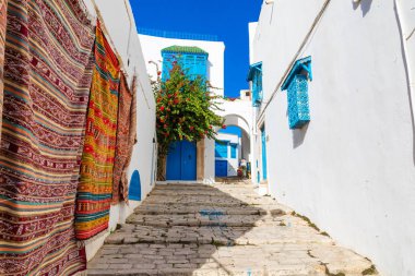 Geleneksel Tunesian halılar mavi tatil beldesi Sidi Bou Said duvarlarda asılı. Tunus, Kuzey Afrika.