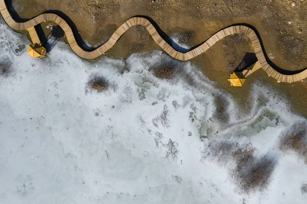 ドローンで撮影した上から木製の桟橋が付いている湖の凍結冬の空撮 — ストック写真