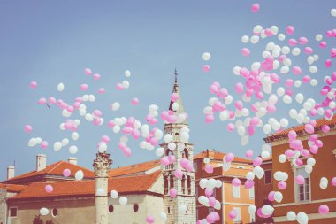 Tarihi merkezinde mavi bir gökyüzünde pembe ve beyaz balonlar 