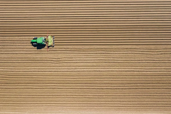 Aerial view of farming tractor plowing and spraying on field.  A — Stock Photo, Image