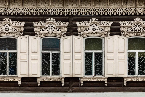 Fenster mit dem geschnitzten Holzarchitrav im alten Holzhaus — Stockfoto