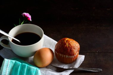 Beyaz fincanda sade kahve, yumurta ve muz keki koyu arka planda izole edilmiş, sosyal mesafe kavramı..